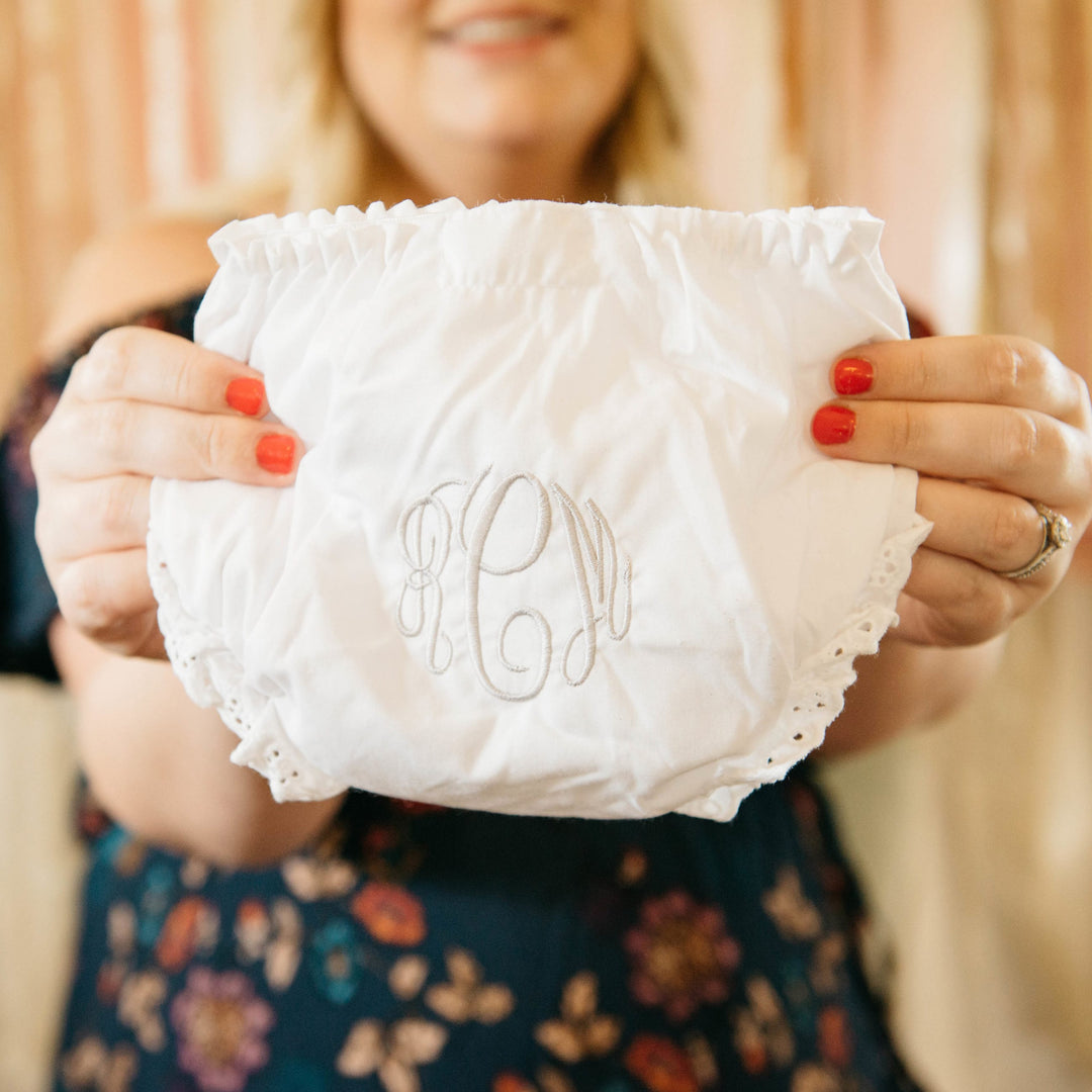 Monogrammed baby gift, white ruffled bloomers held in two hands