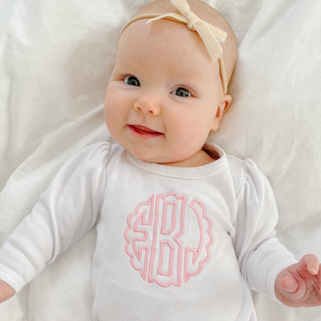 Monogrammed baby bodysuit in white with a pink monogram