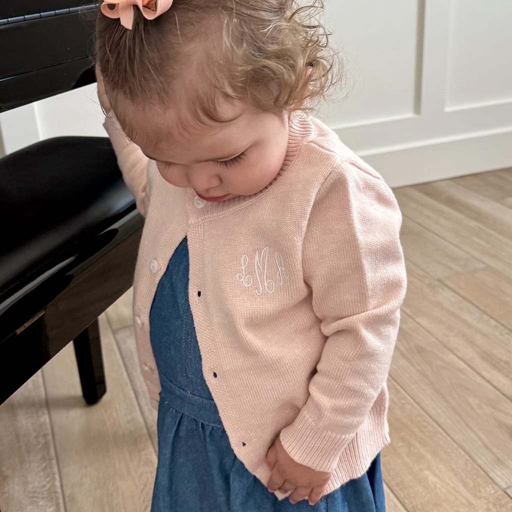 Little girls wearing a blush pink sweater with a white monogram