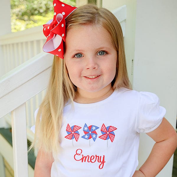 Emery wearing a patriotic shirt with pinwheels and a red bow.