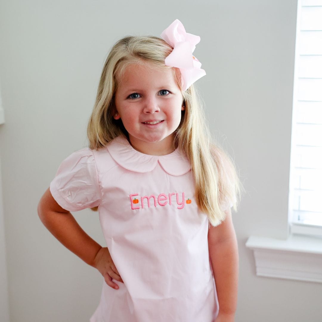 Young girl wearing a pink dress with embroidery